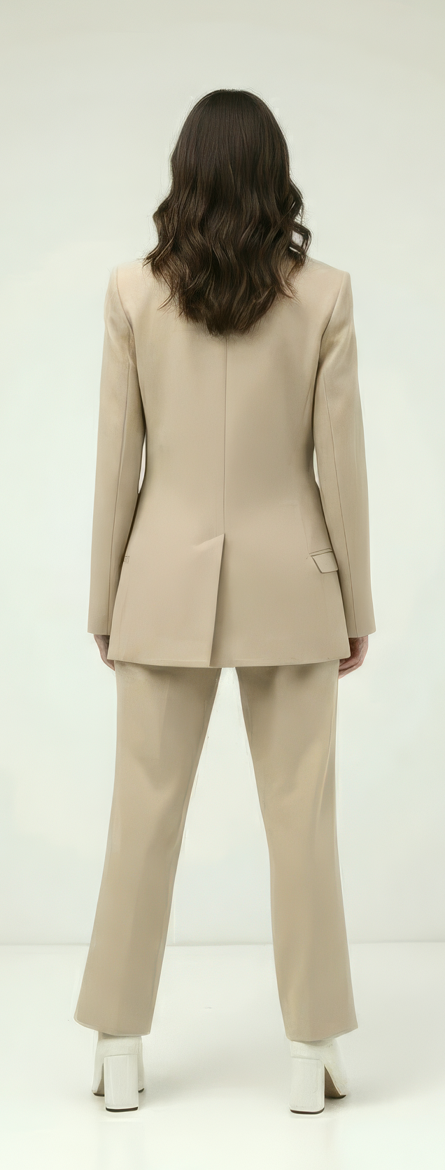 Woman wearing a beige suit standing against a white background